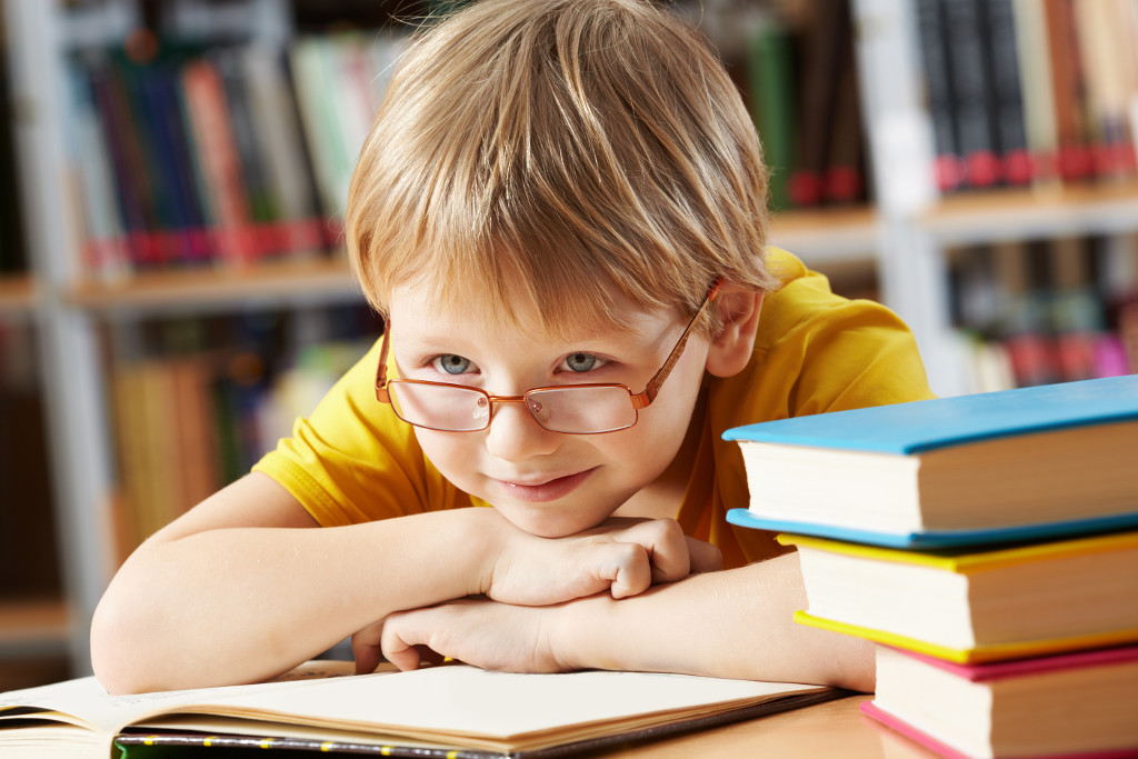 Portrait of clever boy with open book in library